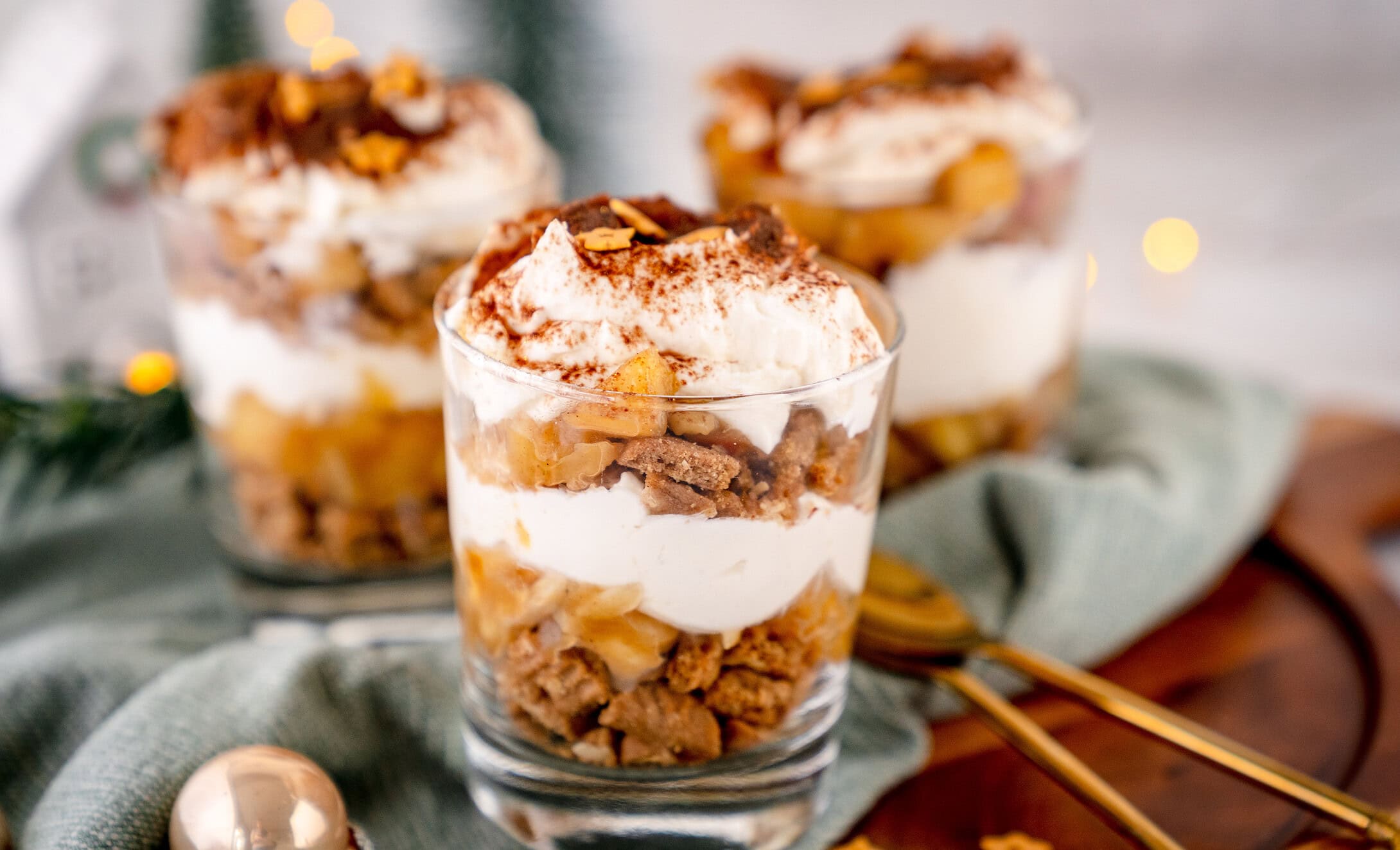 Geschichtetes Bratapfel-Tiramisu in Gläsern auf einem Holzbrett