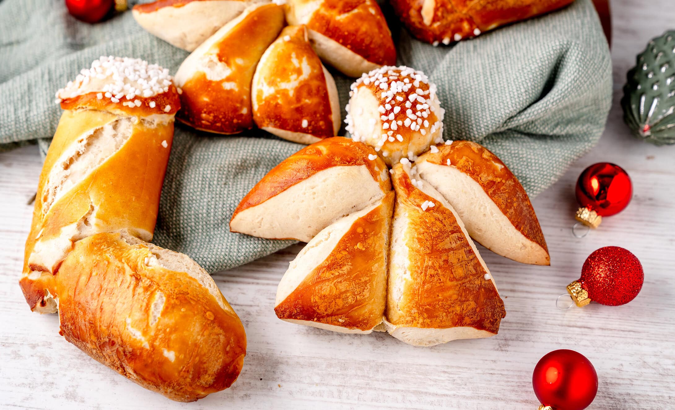 Frische Weihnachtsbrötchen auf weissem Holz mit festlicher Dekoration, traditionelles Gebäck. Laugengebäck Weihnachten Lausebengel Nikolausstiefel