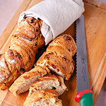 Frisches Zwiebel-Speck-Baguette, aufgeschnitten, auf Holzbrett, mit Brotmesser-Neuheit.