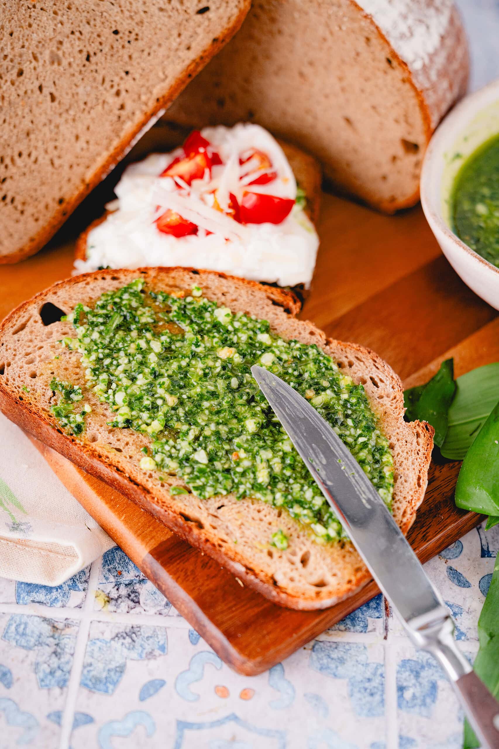 Grünes selbstgemachtes Bärlauchpesto auf einem Stück Brot