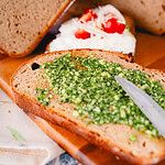 Bärlauchpesto, das mit Pinienkernen und Parmesan auf eine Brotscheibe gestrichen wird