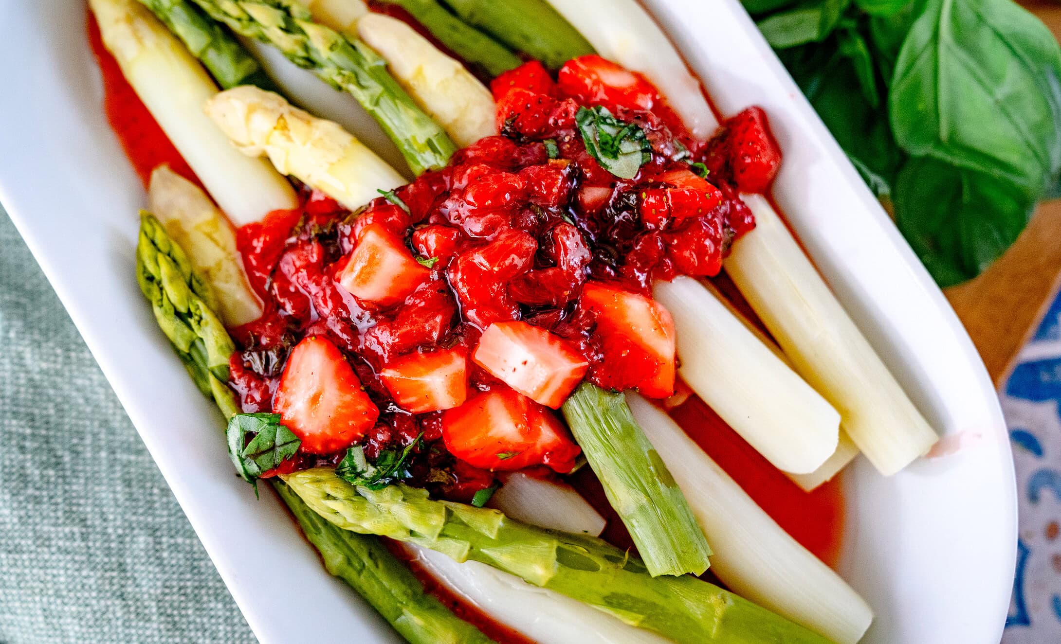 Erdbeer Chutney verteilt auf einem länglichen weißem Teller mit grünem und weißem Spargel